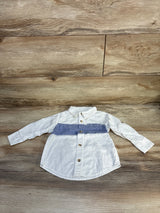 White long sleeve kids shirt with blue stripe and buttons, laid on wood surface
