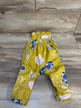 Yellow floral baby romper with blue and pink flower print on wooden floor