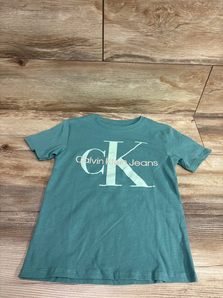 Front view of green Calvin Klein Jeans shirt in size 5T showcasing a large Calvin Klein Jeans logo on a wood background