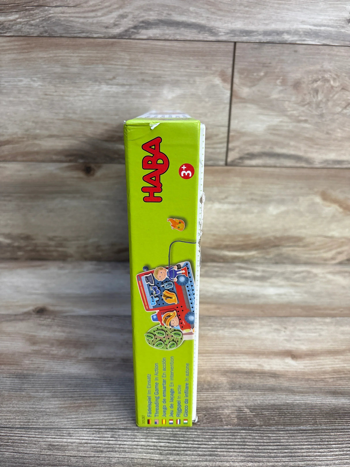 Side of HABA Threading and Lacing Game box showing 3+ age label and colorful lacing-piece illustration on wooden background