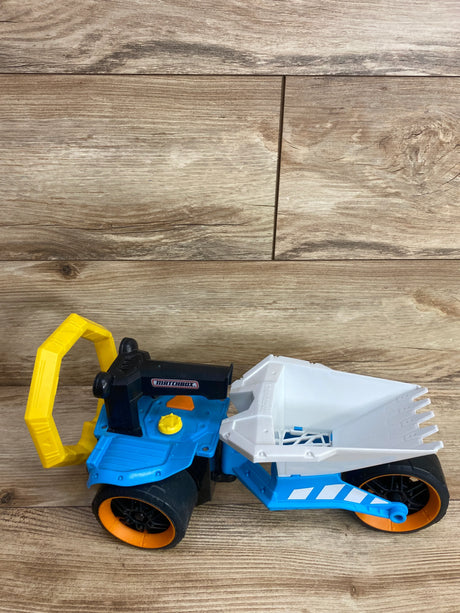 Matchbox toy dump truck with blue, white, black, orange, and yellow parts on wooden floor