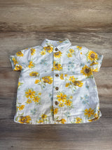 Short sleeve baby shirt with yellow floral print and buttons on wood background