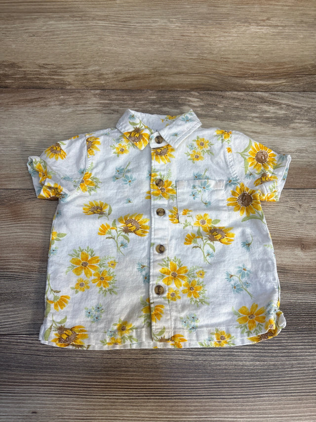 Short sleeve baby shirt with yellow floral print and buttons on wood background
