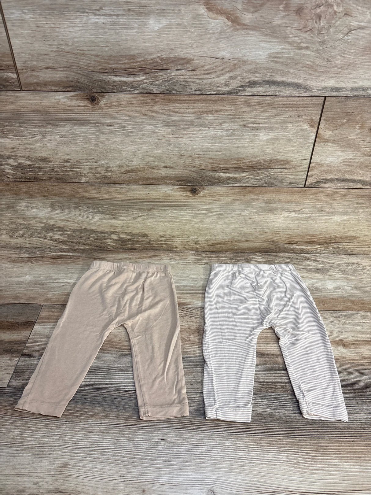 Baby girl pants: solid beige and gray striped leggings on wood floor