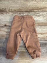 Soft brown kids joggers with elastic waist and cuffs, laid on wood floor