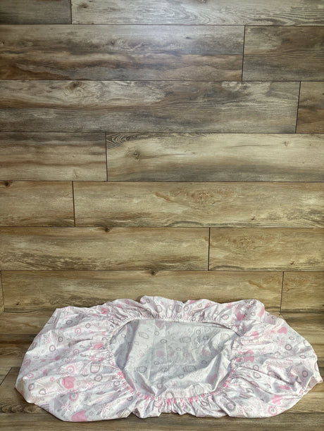 Flat lay of The Peanutshell fitted crib sheet in white with pink and grey fox and owl print on wood plank floor