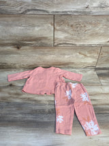 Pink long sleeve baby top and floral pants set on wood background