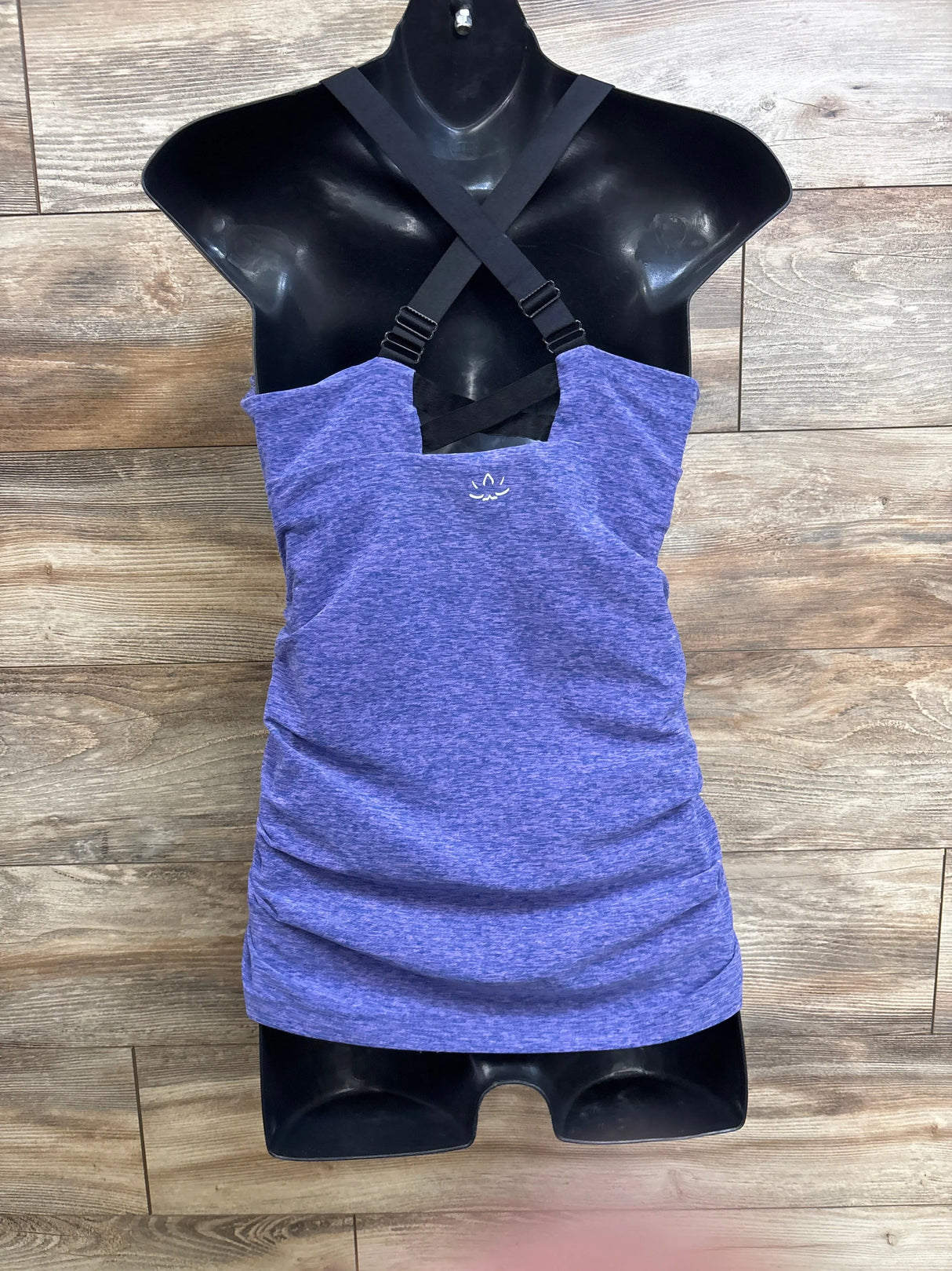 Front view of purple maternity cami with cross-back adjustable straps and ruched sides on black mannequin, wood background