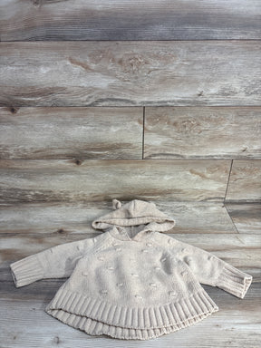 Beige knitted baby hoodie with textured dots and ribbed hem on wooden floor
