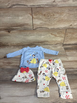 Flat lay of 3-piece Disney set: blue Snow White top 'Cutest of All', printed pants and hat with red bow on wood