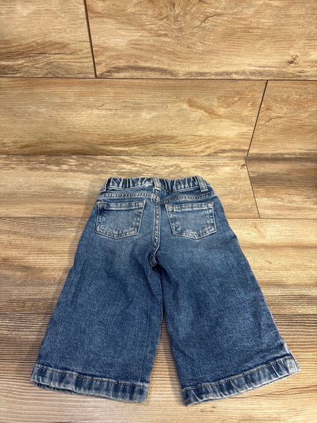 Back view of Cat and Jack wide-leg blue toddler jeans, 12 months, showing elastic waistband, back pockets, and faded hems on wood floor