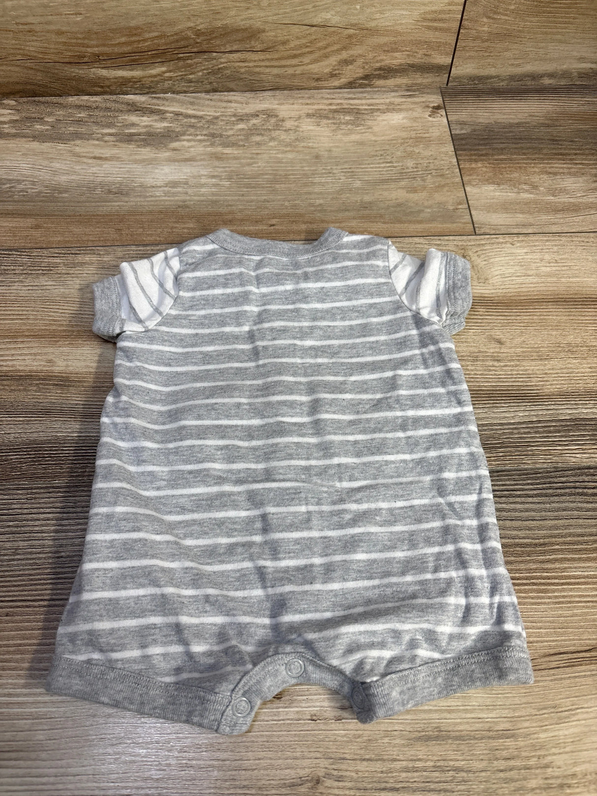 Back view of newborn grey striped Carter's romper showing short sleeves and snap crotch on wood floor