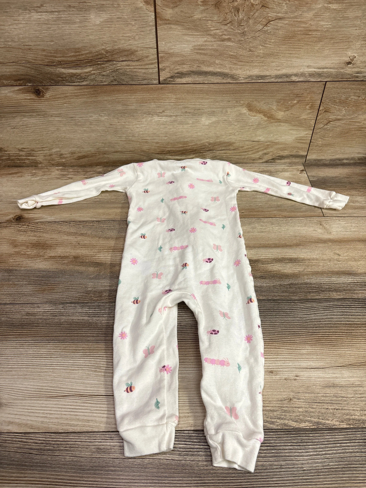Top view of white Just One You sleeper, size 18 months, with long sleeves and colorful floral and insect prints on wood flooring