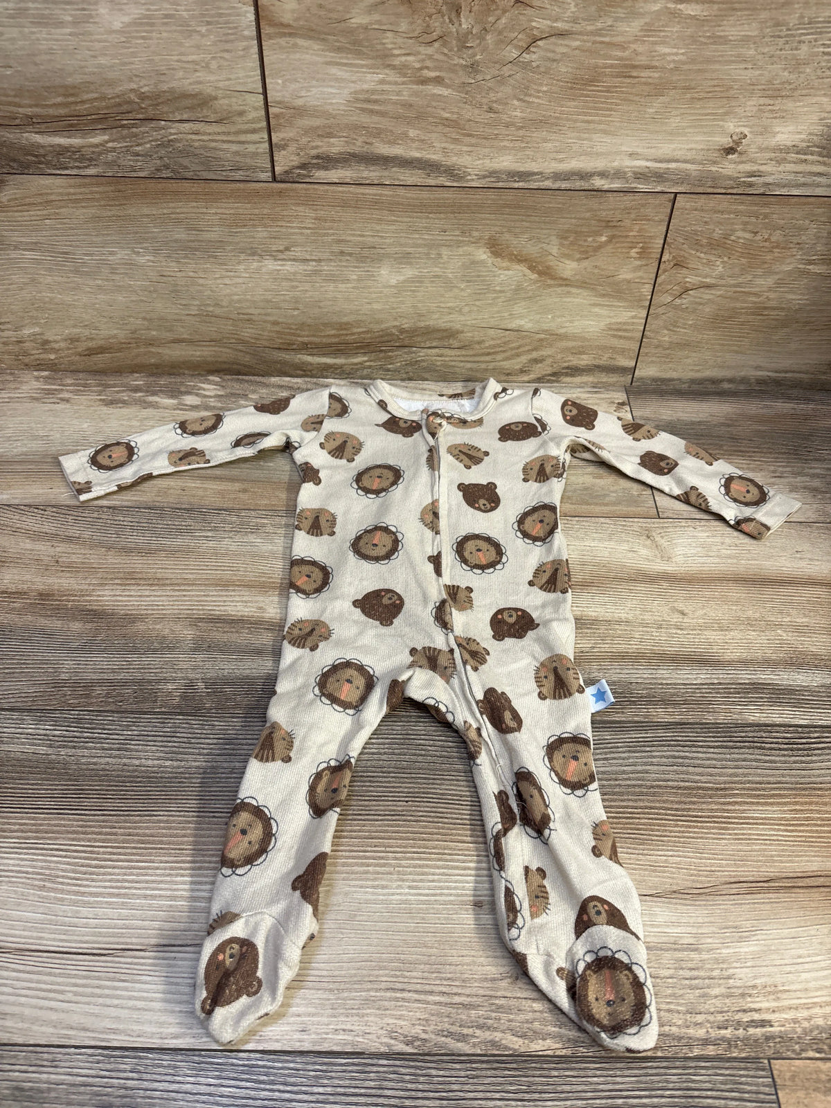 Front view of Millie & Myles tan sleeper, size 3-6m with long sleeves, front zipper, and lion and bear print on wood floor