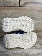 Kids athletic shoes with white rubber soles and grid tread on wood floor