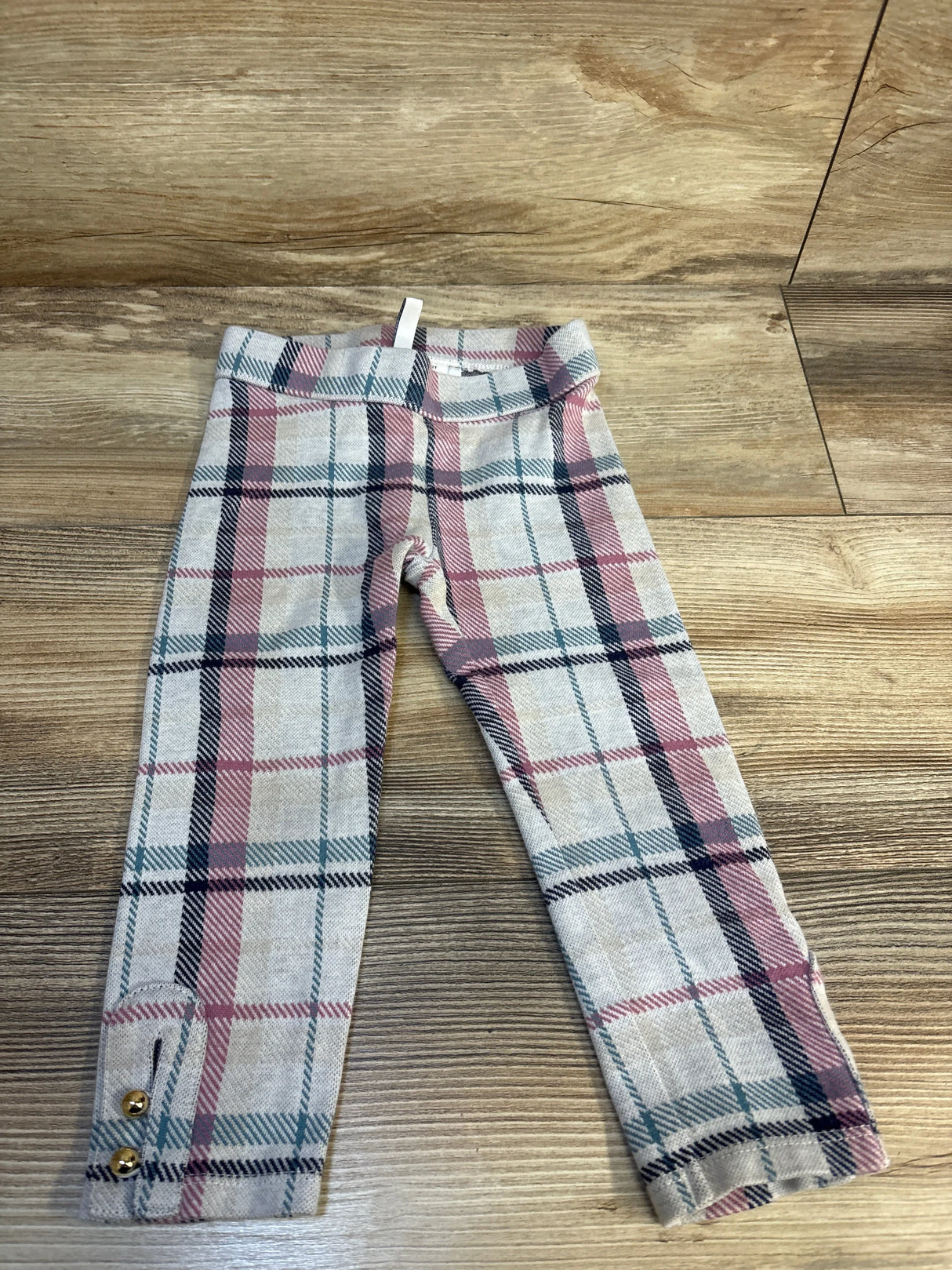 Girls plaid leggings with pink and navy check pattern and gold button details on cuffs