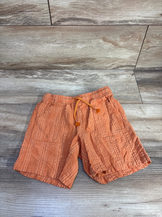 Flat lay of orange Cat & Jack drawstring textured toddler shorts showing front pockets and elastic waistband on wood background