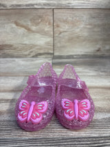 Front view of pink Old Navy jelly Mary Jane flats size 5C showcasing glittered translucent material and butterfly charms on wood floor