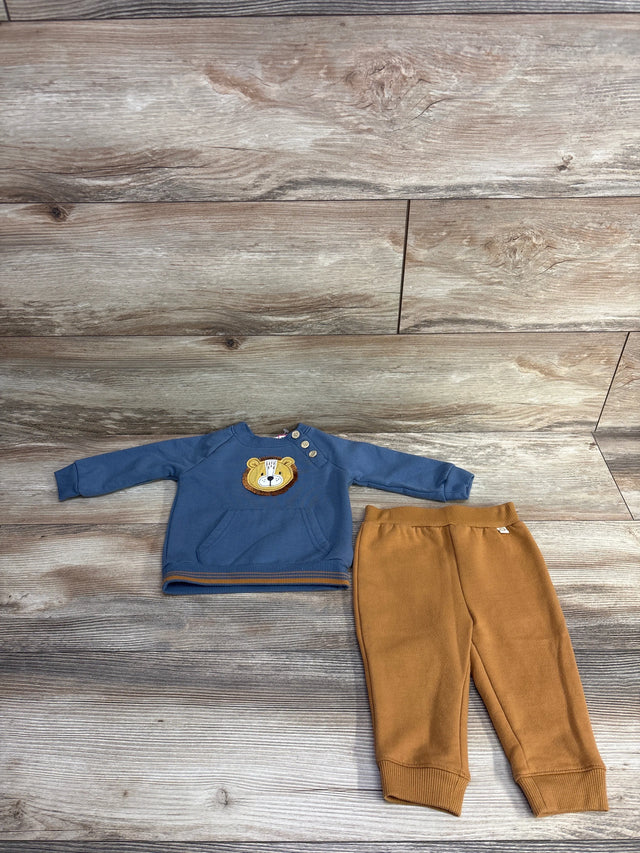 Baby outfit with blue sweatshirt featuring lion face and brown pants on wood floor