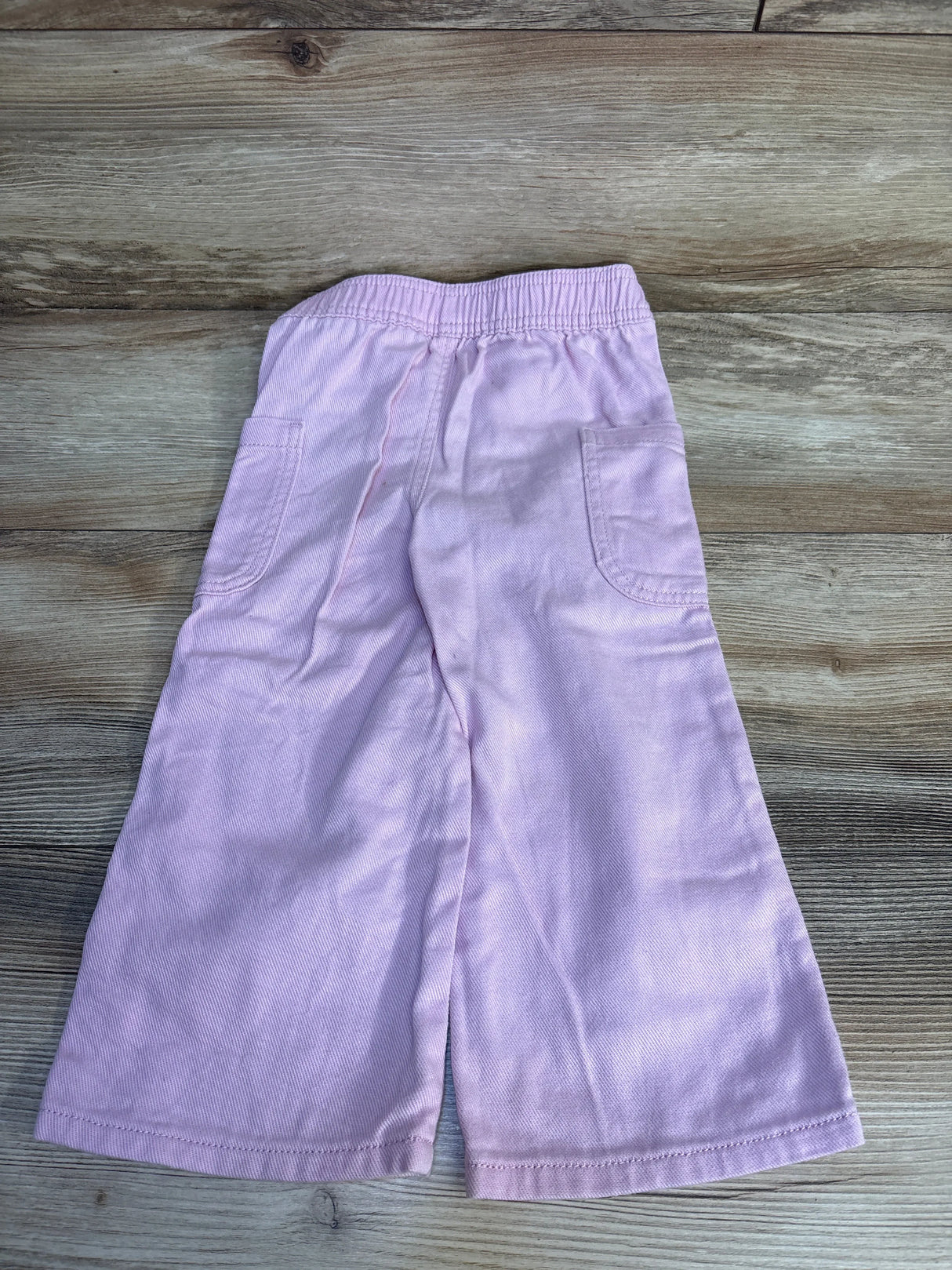 Light purple kids shorts with elastic waist and side pockets, laid on wood floor