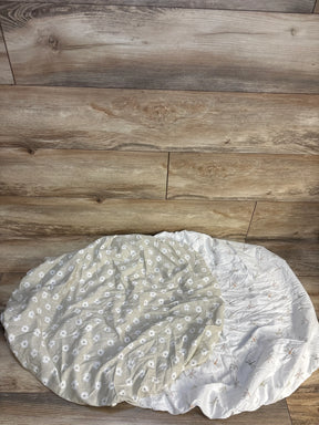 Two fitted crib sheets, one with white daisies on beige, one with dragonflies on white, on wood floor