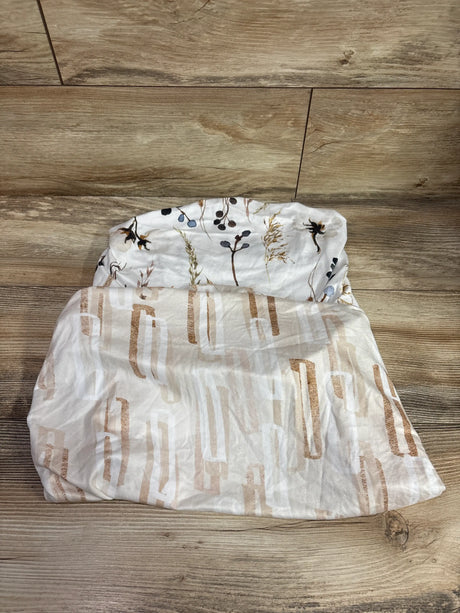 Top view of GRSSDER 2pk fitted bassinet sheets in white and tan, showing botanical and geometric patterns on a wood floor