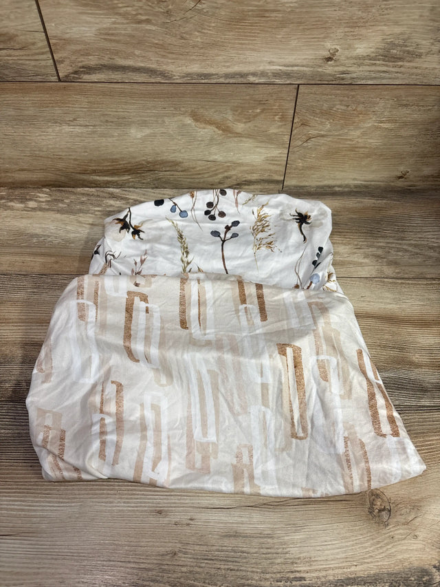 Top view of GRSSDER 2pk fitted bassinet sheets in white and tan, showing botanical and geometric patterns on a wood floor