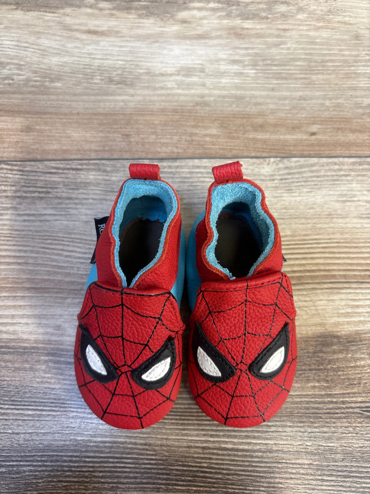 Spider-Man baby shoes with red web design and blue soles, perfect for little superhero fans.