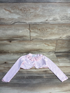 Light pink long sleeve bolero for girls with rosette trim, laid flat on wood background