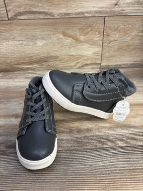 Black children's high-top sneakers with white soles and laces on wood background