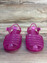 Front view of Janie & Jack Jelly Fisherman sandals showing translucent pink caged toes and ankle buckle straps on a wood background