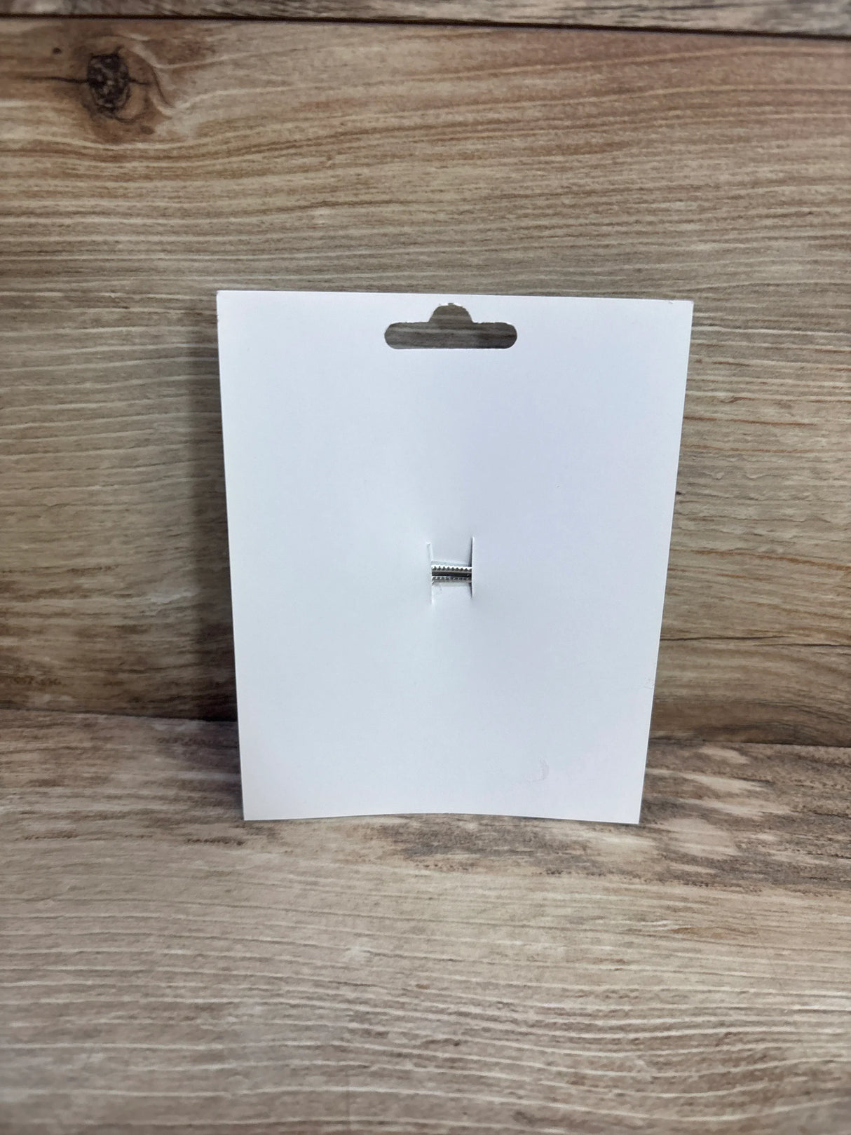 Front view of white birthday hair bow packaging showing attached silver alligator clip on wood background