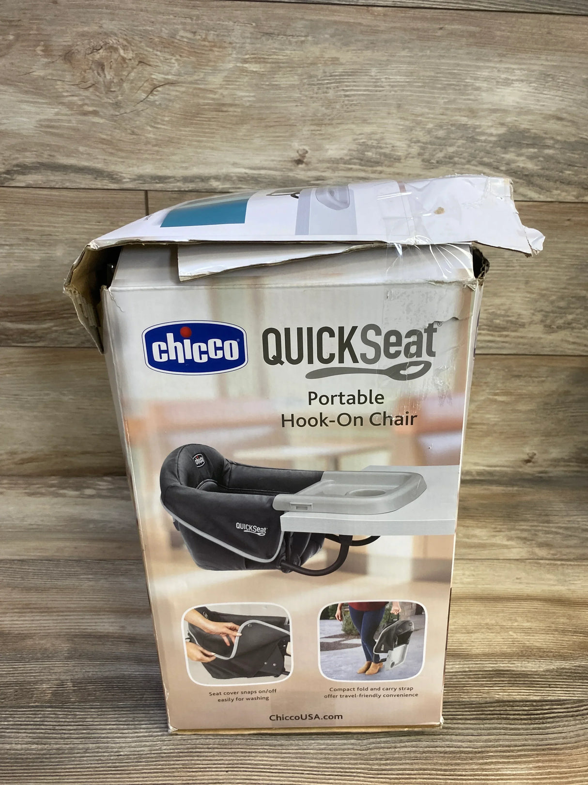 Front view of Chicco QuickSeat portable hook-on chair showing teal chair with attached tray on wood background