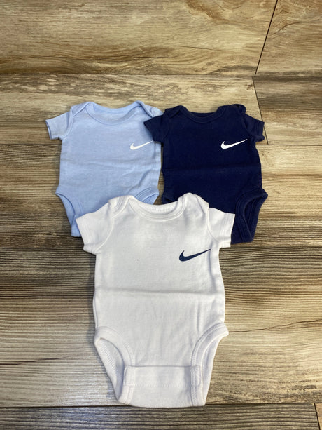 Three baby bodysuits in blue, navy, and white with logo on wooden floor