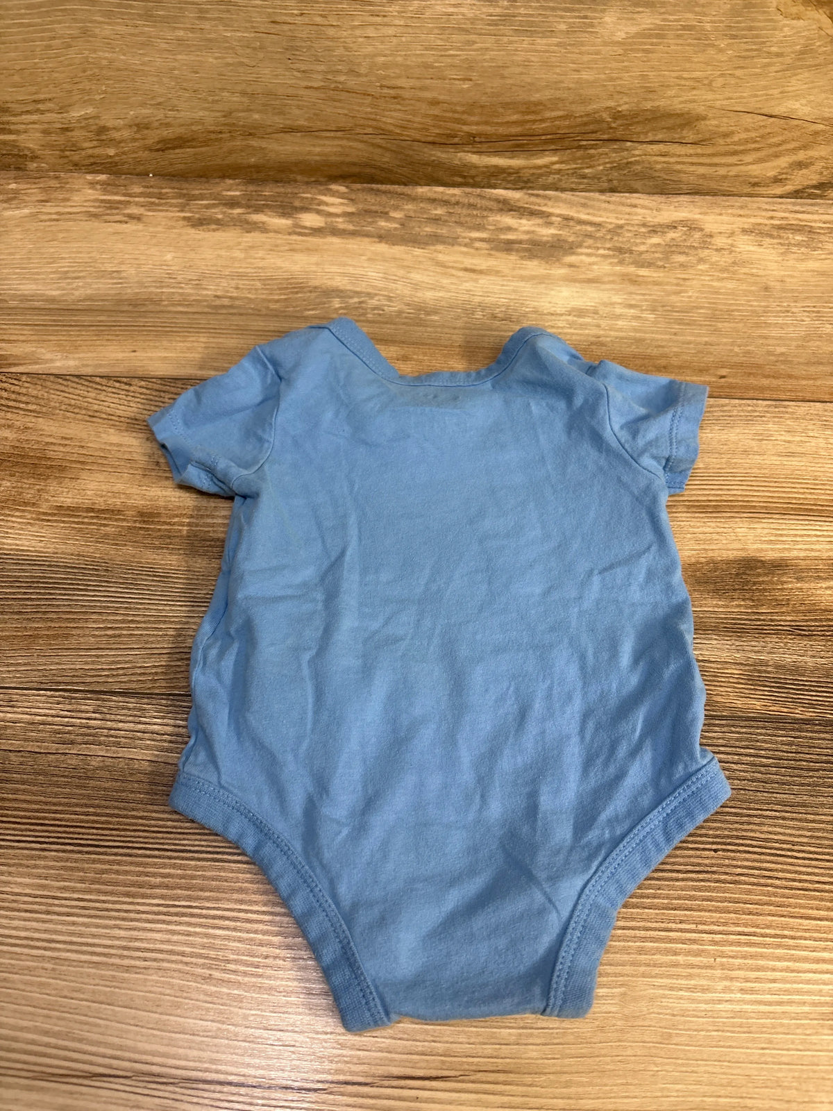 Light blue Nike baby bodysuit size 6m laid flat on a wooden surface