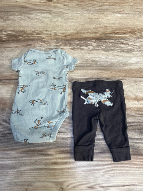 Baby boy airplane bodysuit and black pants set on wood background