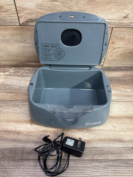 Open view of Hiccapop Ultra Wipe Warmer in grey showcasing hinged lid, empty basin, front cover, and power adapter on a wood floor