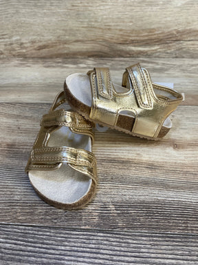 Gold toddler sandals with adjustable straps and cork soles on wood background