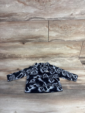 Black and white Adidas toddler jacket with all-over logo print on wooden floor background