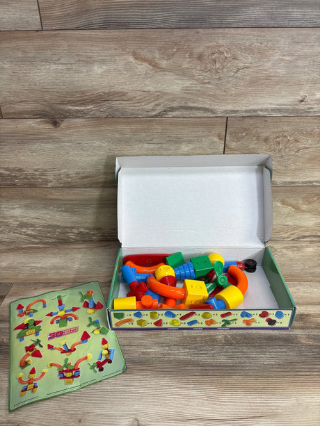 Open box of colorful plastic building blocks with instruction sheet on wood floor