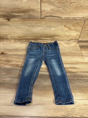 Flat lay of 7 For All Mankind toddler jeans, size 24 months, showing faded knees and rolled cuffs on light wood floor
