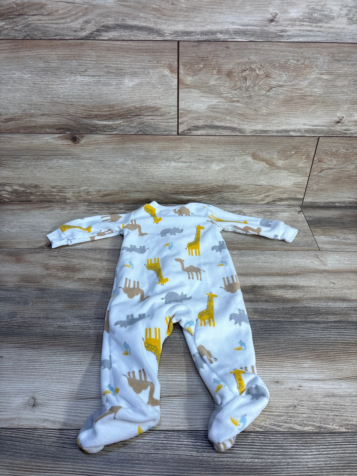 Top-down view of white footed blanket sleeper showcasing yellow giraffe and gray animal print on wood plank background