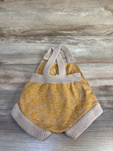 Flat lay of beige and mustard knit baby bubble romper with crossed straps, ribbed trim, and button closure on wood