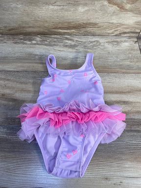 Top-down view of Cat & Jack purple one-piece toddler swimsuit with pink layered tulle tutu and pink heart print on wood background