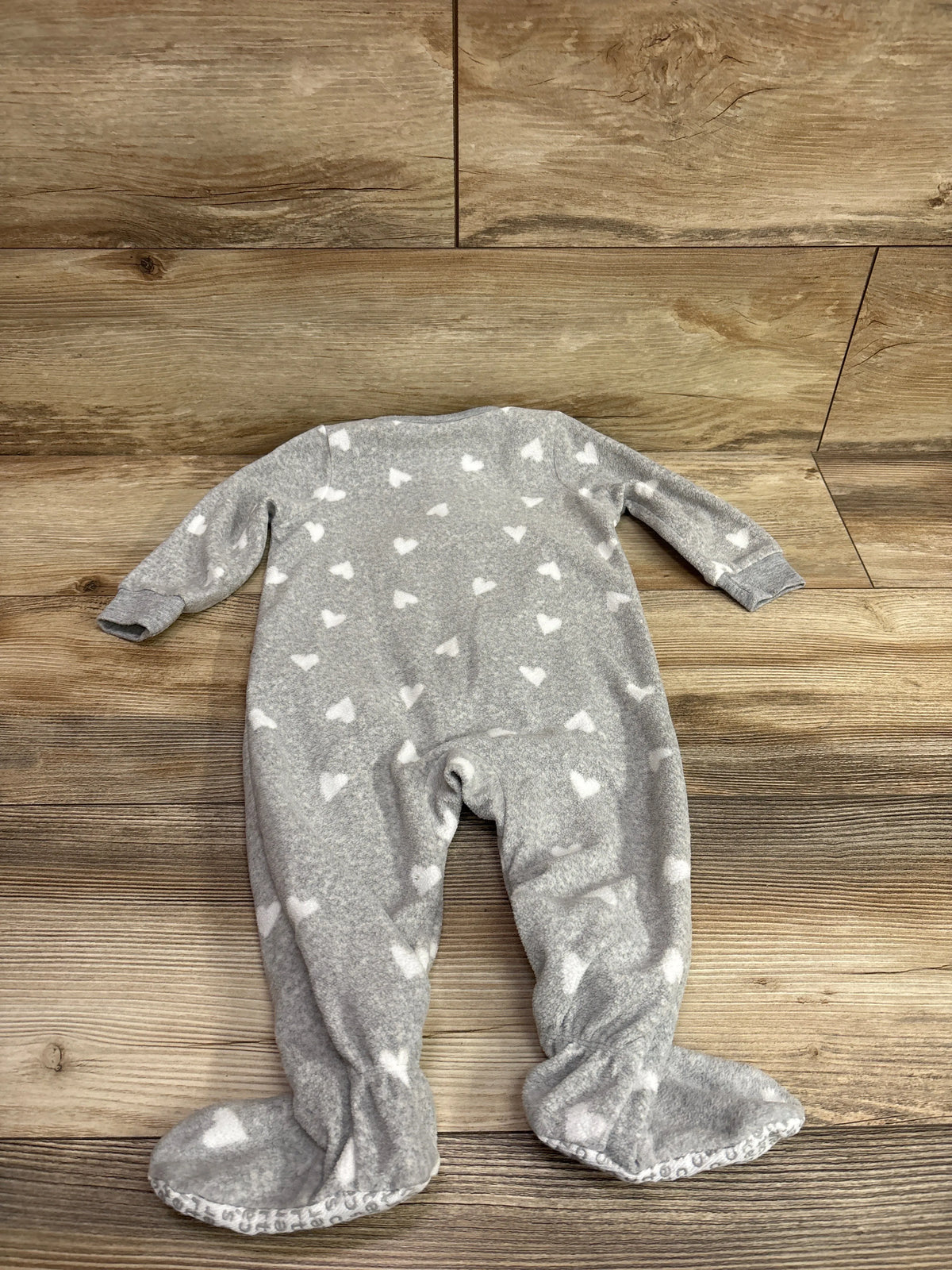 Full view of Carter’s grey blanket sleeper, size 12 months, with white hearts and attached footies on wood flooring
