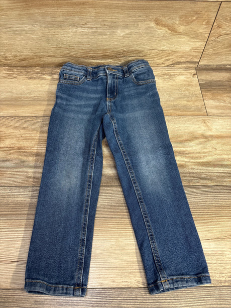 Gently used children's blue denim jeans laid flat on wooden floor, kids clothing resale
