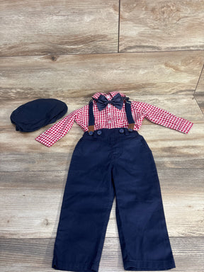 Children's outfit with red checkered shirt, navy blue pants with suspenders, bow tie, and matching navy cap on wooden floor