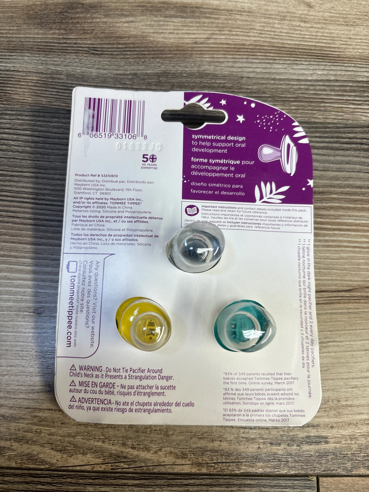 Tommee Tippee baby pacifiers in packaging, yellow and teal, on wood surface