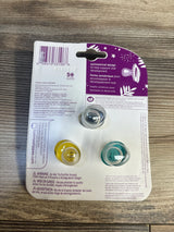 Tommee Tippee baby pacifiers in packaging, yellow and teal, on wood surface