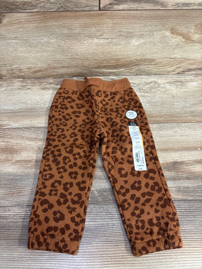 Brown and dark brown leopard print baby pants with elastic waist and cuffs on wooden floor